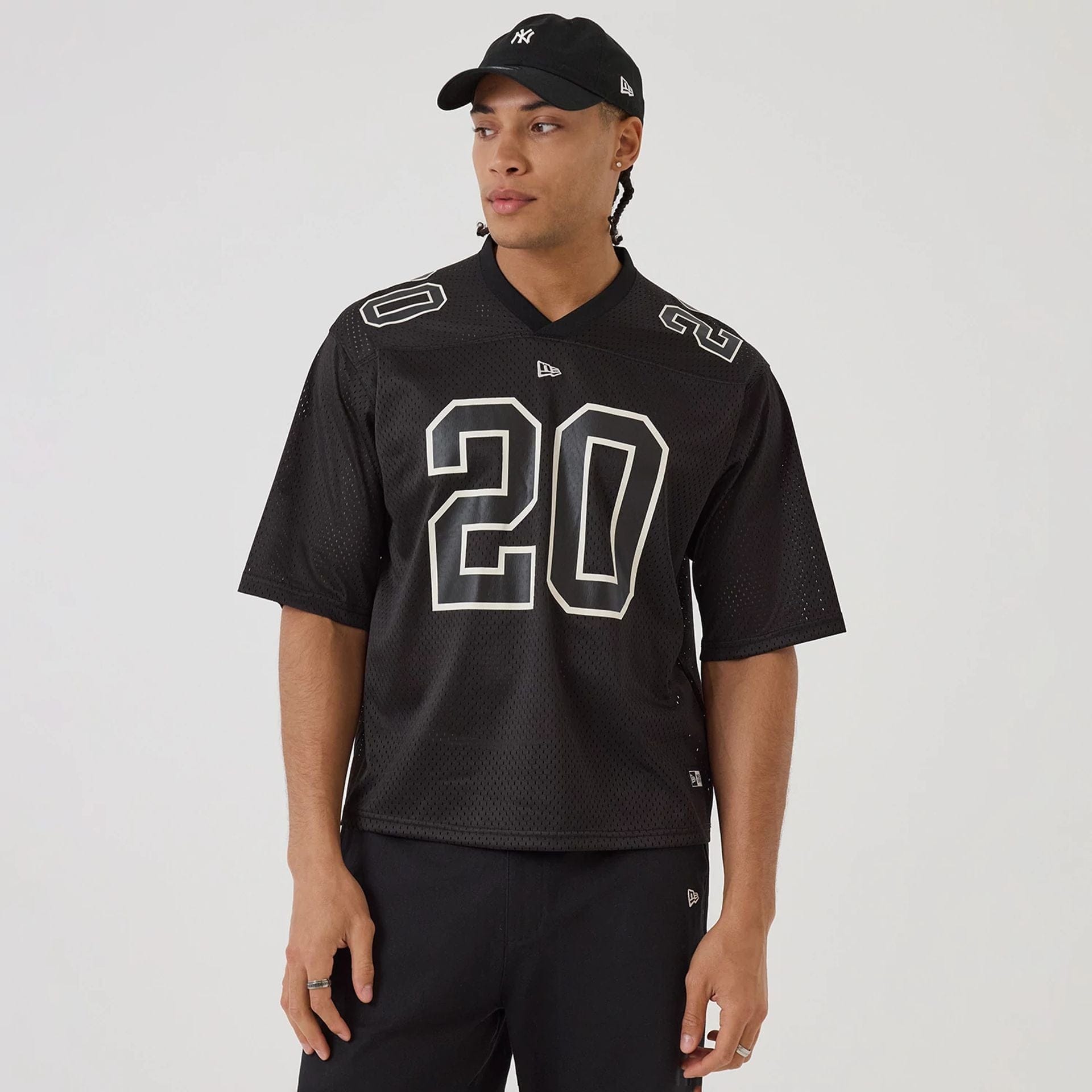 The model is wearing this New Era Mesh Football Short Sleeve Shirt in black. 1