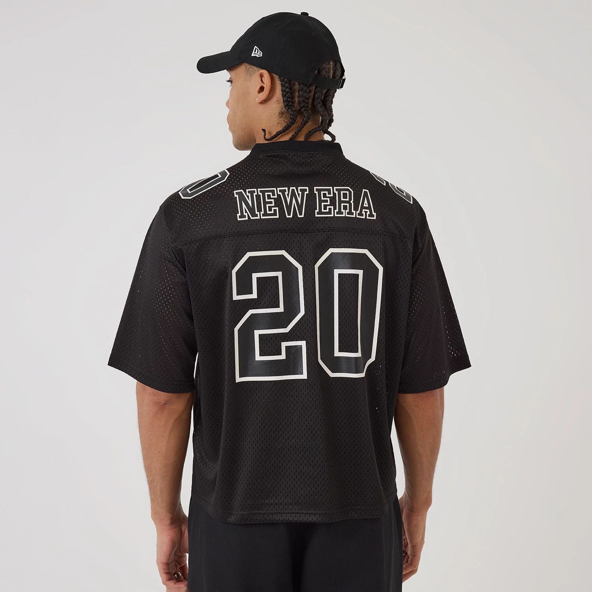 The model is wearing this New Era Mesh Football Short Sleeve Shirt in black. 2