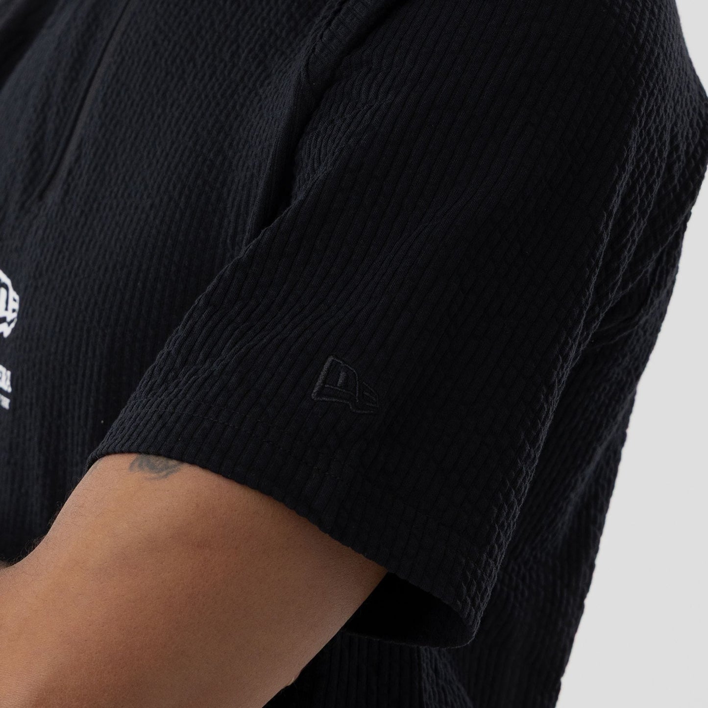 The model is wearing this New Era Seersucker Polo T-Shirt in black. 5