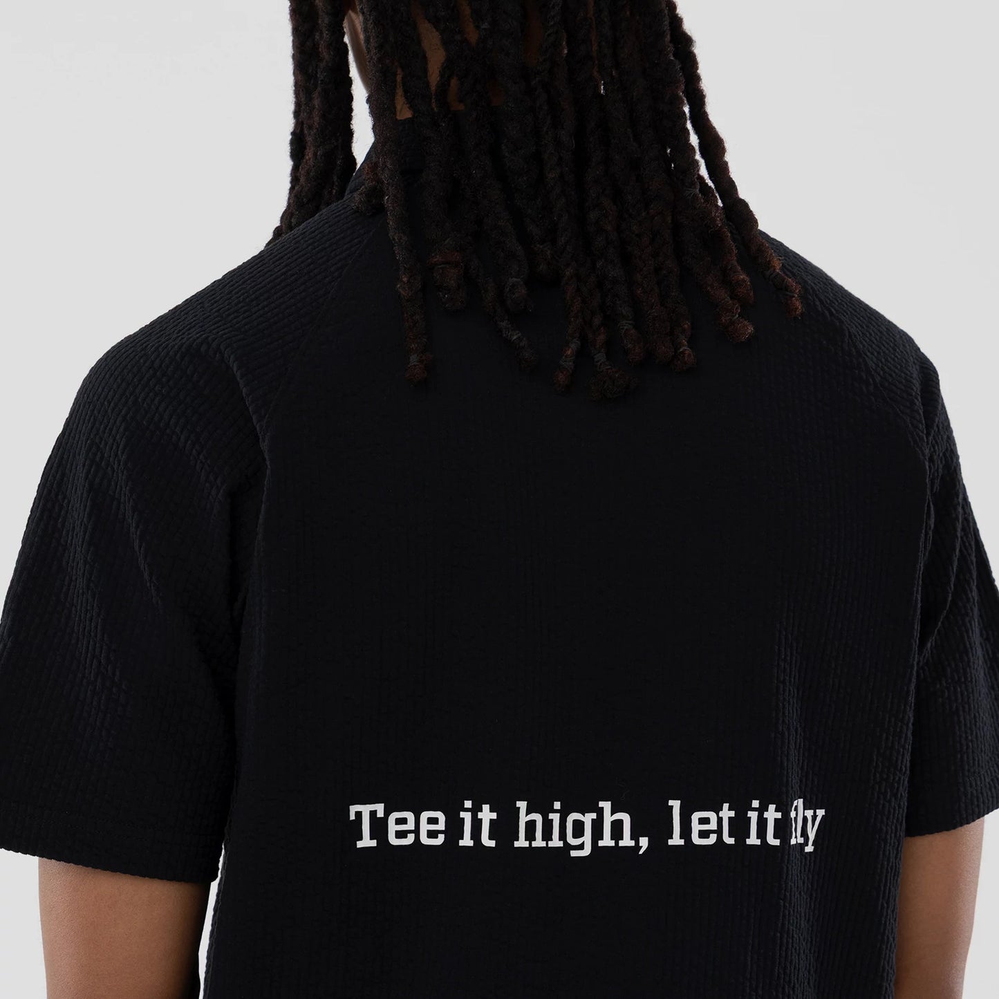 The model is wearing this New Era Seersucker Polo T-Shirt in black. 6