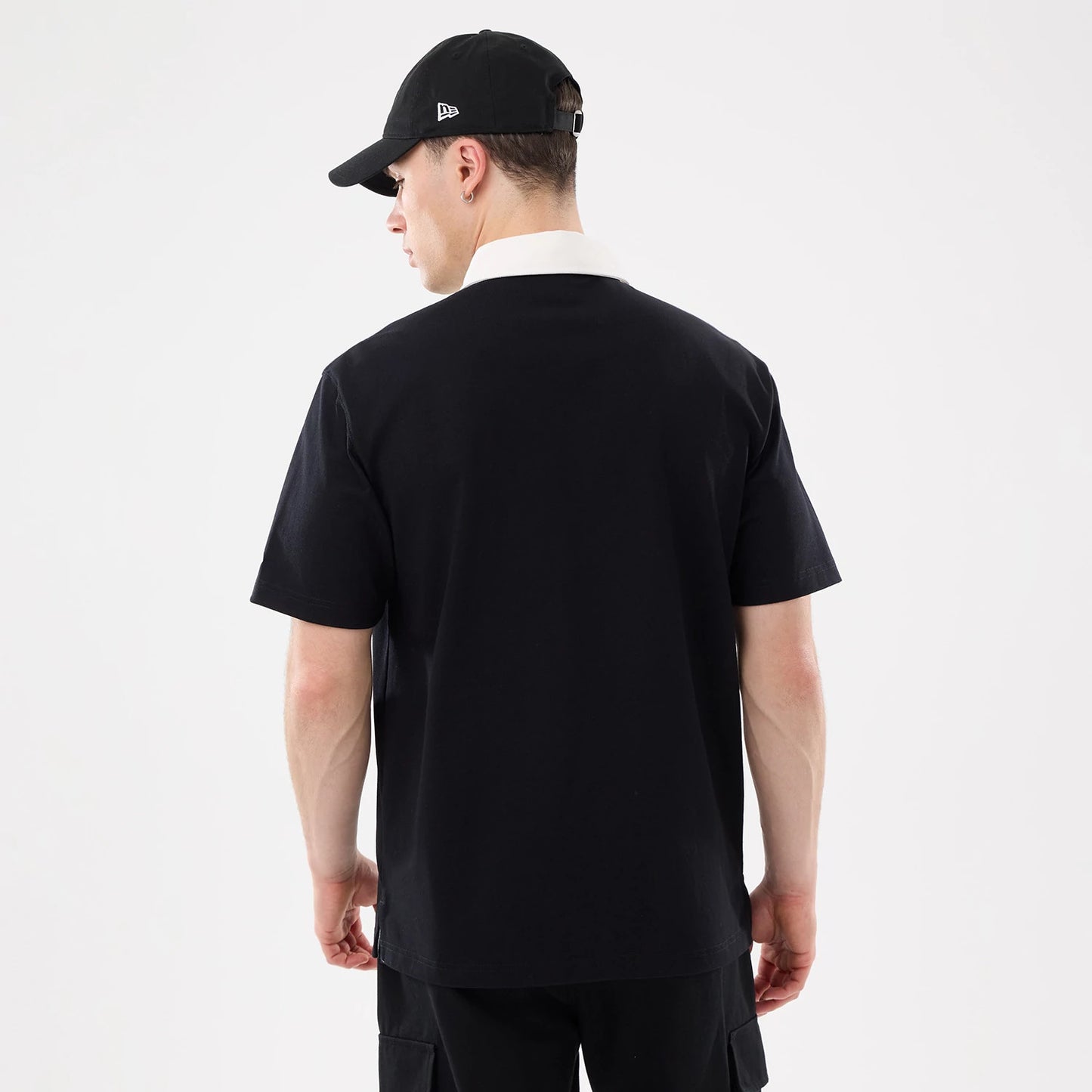 The model is wearing this New Era Short Sleeve Rugby Shirt in black. 2