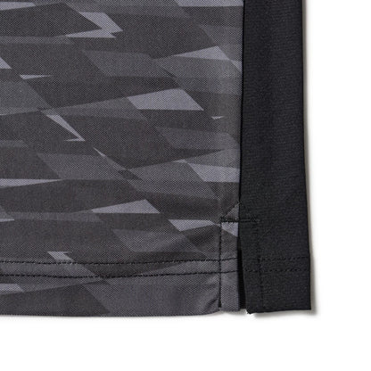 New Era Grid Black Polo T-Shirt, side view showing the bottom hem with a geometric black and grey pattern, a small slit detail at the seam, and contrasting black fabric on the right edge.