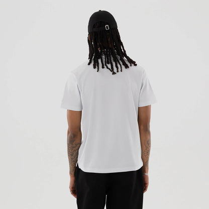 New Era Kanoko White Polo T-Shirt, rear view with a clean white back, short sleeves, and a black embroidered logo near the neckline, worn by an individual in black trousers and a black cap.