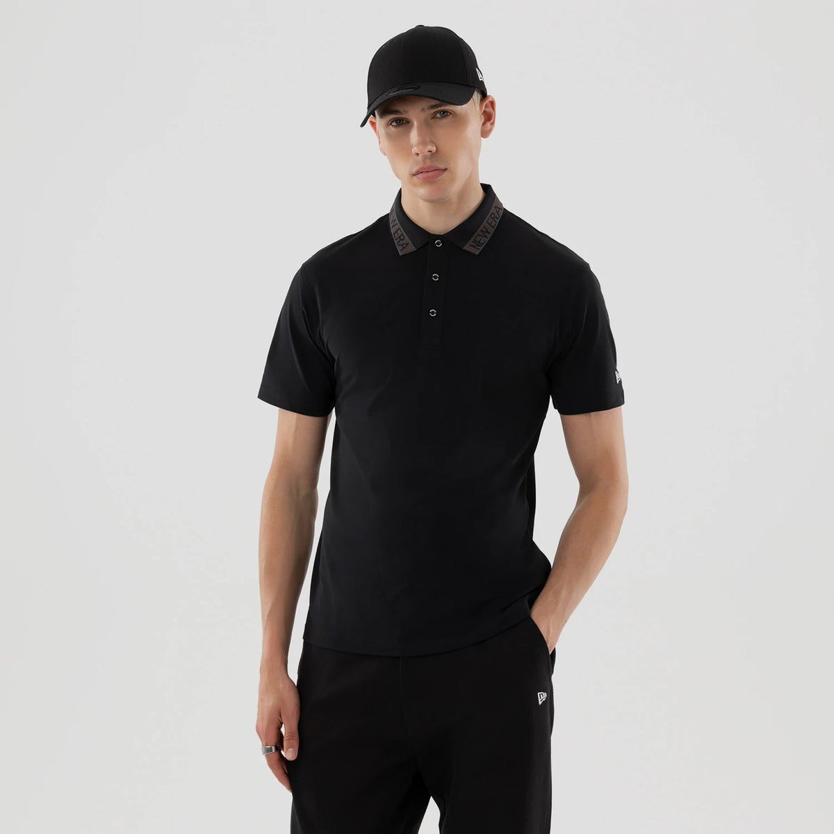 New Era Kanoko Black Polo T-Shirt, front view showing the black polo with a buttoned collar featuring the raised New Era logo, short sleeves, and a small embroidered New Era logo on the left sleeve.