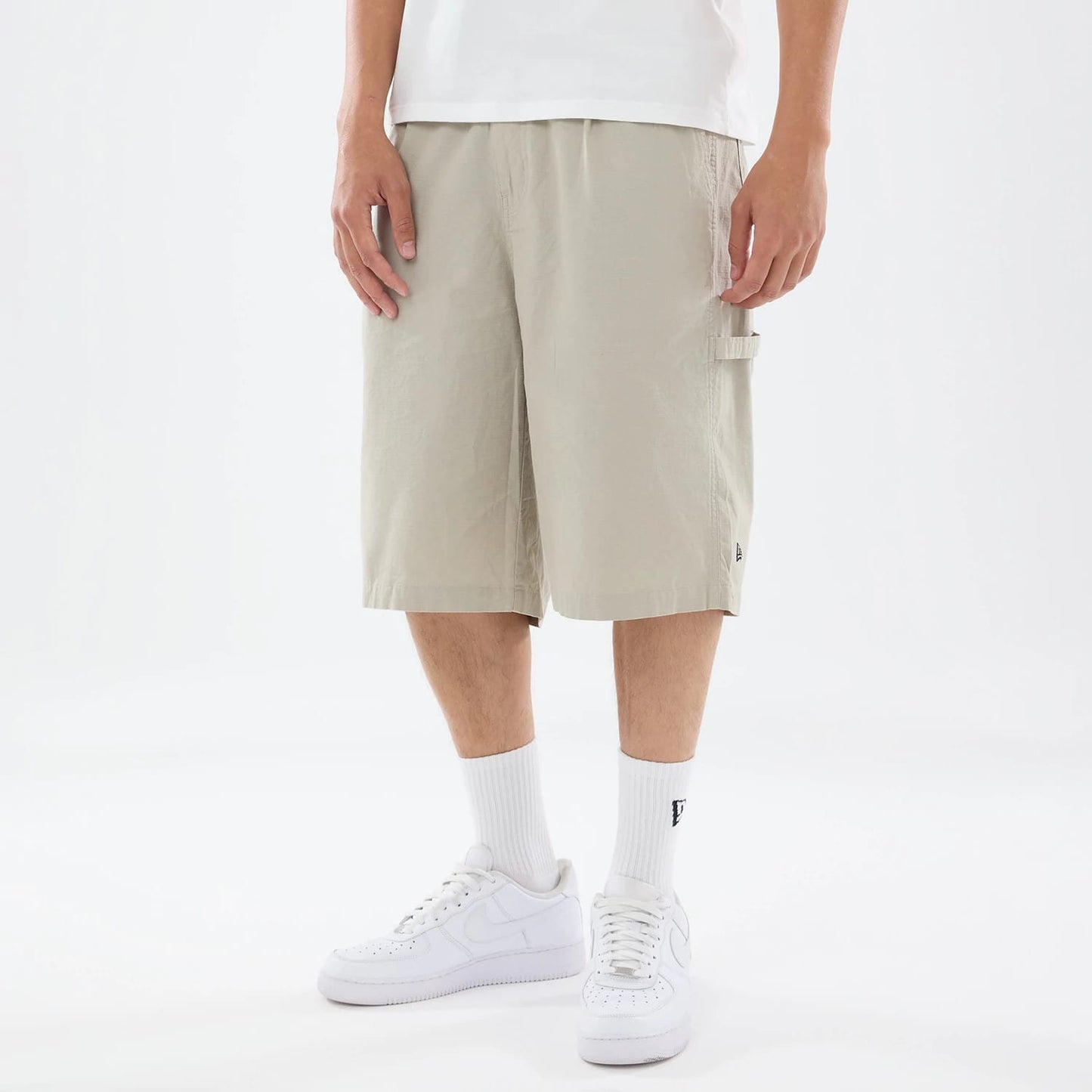 The model is wearing this New Era Canvas Bermuda Shorts in beige. 1