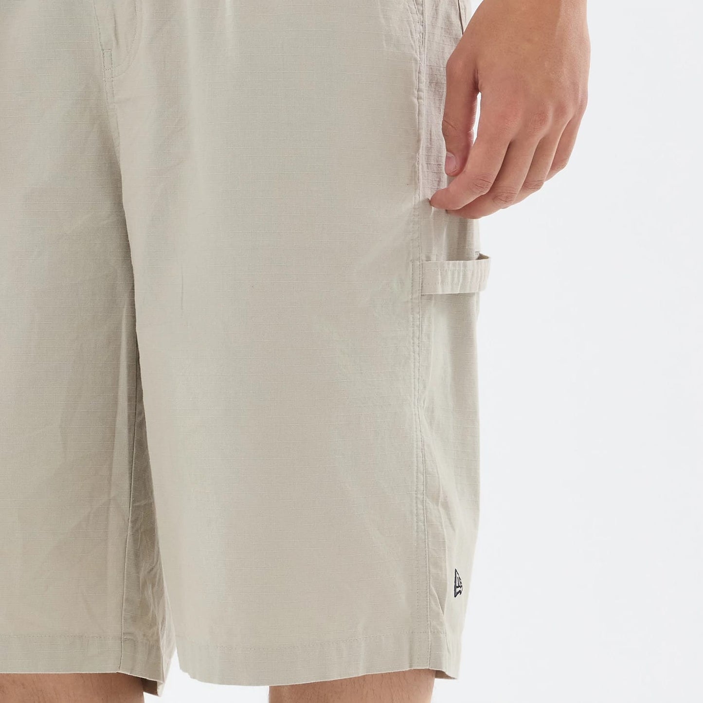 The model is wearing this New Era Canvas Bermuda Shorts in beige. 5
