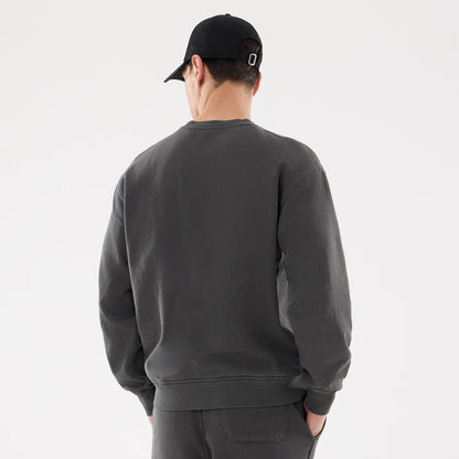 New Era Originators Black Crew Neck Sweater, rear view on a model dressed in matching black trousers and a black cap, showing the plain back design and relaxed fit with ribbed cuffs and hemline.