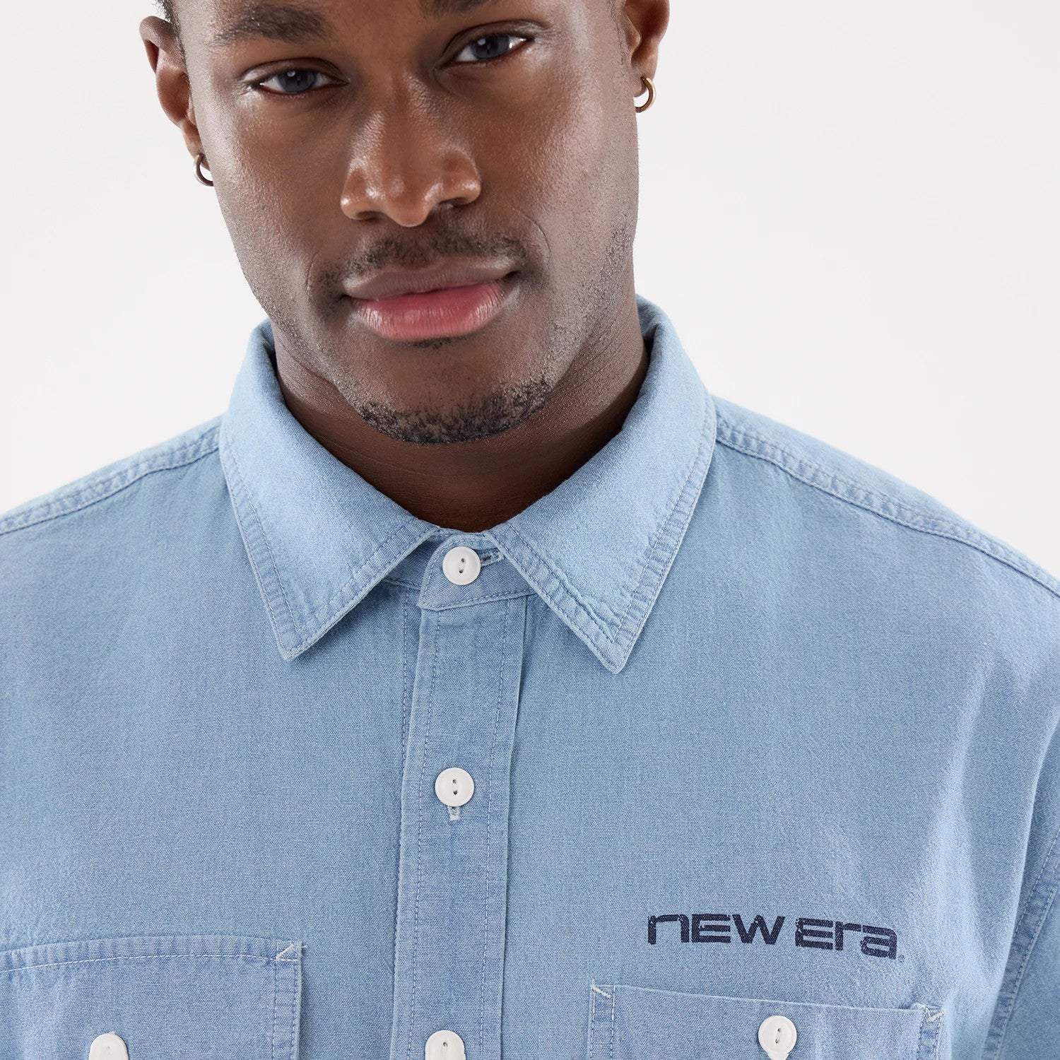The model is wearing this New Era Originators Chambray Short Sleeve Shirt in bright blue. 4
