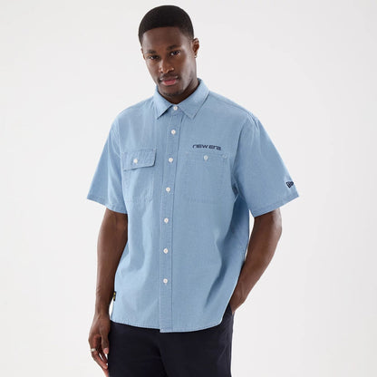 The model is wearing this New Era Originators Chambray Short Sleeve Shirt in bright blue. 1