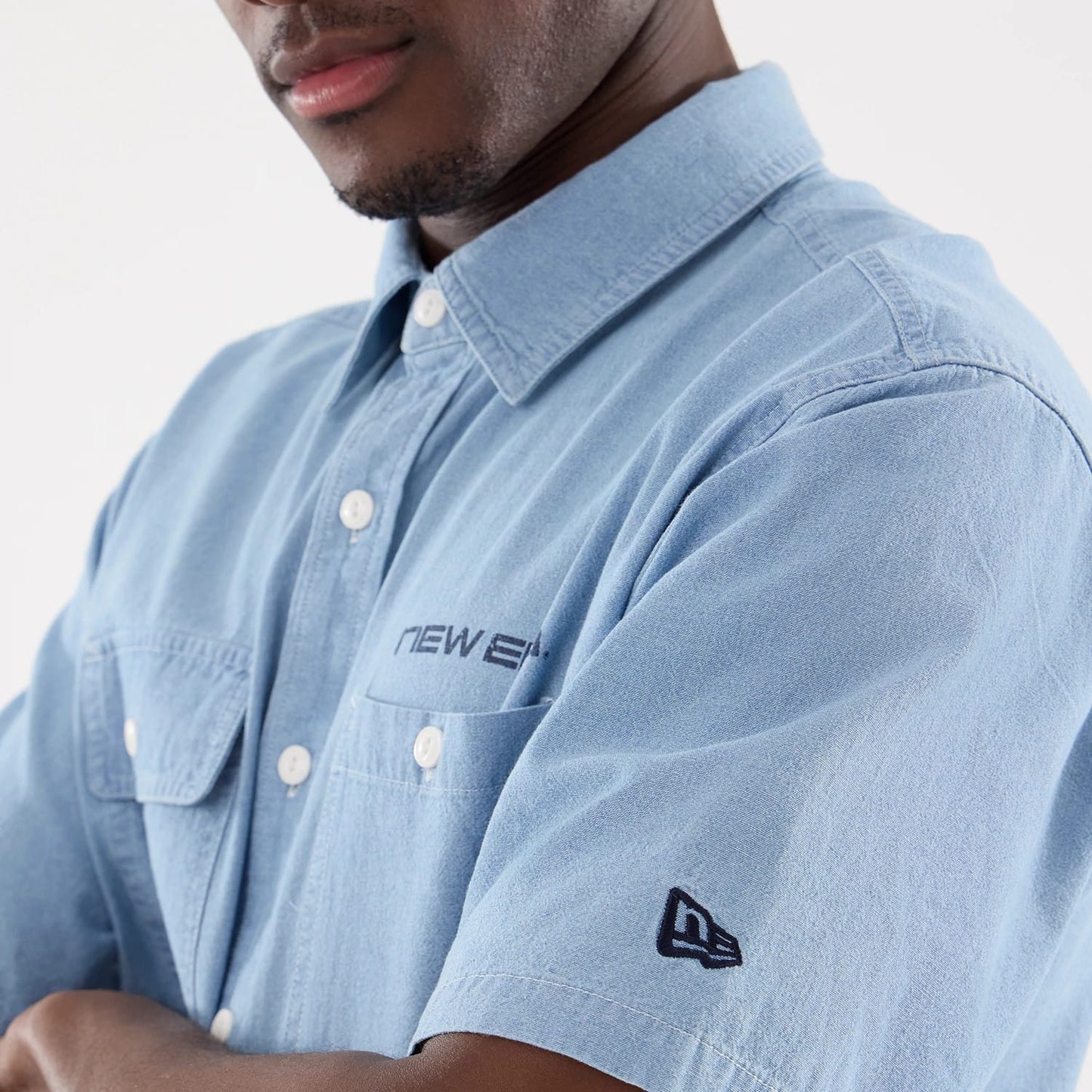 The model is wearing this New Era Originators Chambray Short Sleeve Shirt in bright blue. 5