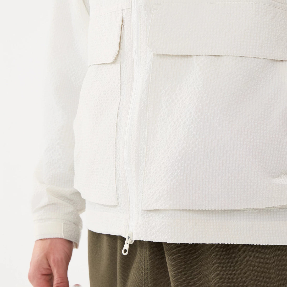 New Era Black Label Open White Jacket, front view showing the textured white fabric with a central zip closure, two chest pockets with flaps on either side, and a long sleeve ending with a straight cuff.