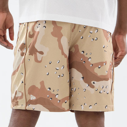 New Era Bermuda Woodland Camo Oversized Shorts, on-model view showing the beige and brown camo pattern across the shorts, with a raised New Era logo on the left leg near the hem and a relaxed fit reaching above the knees.