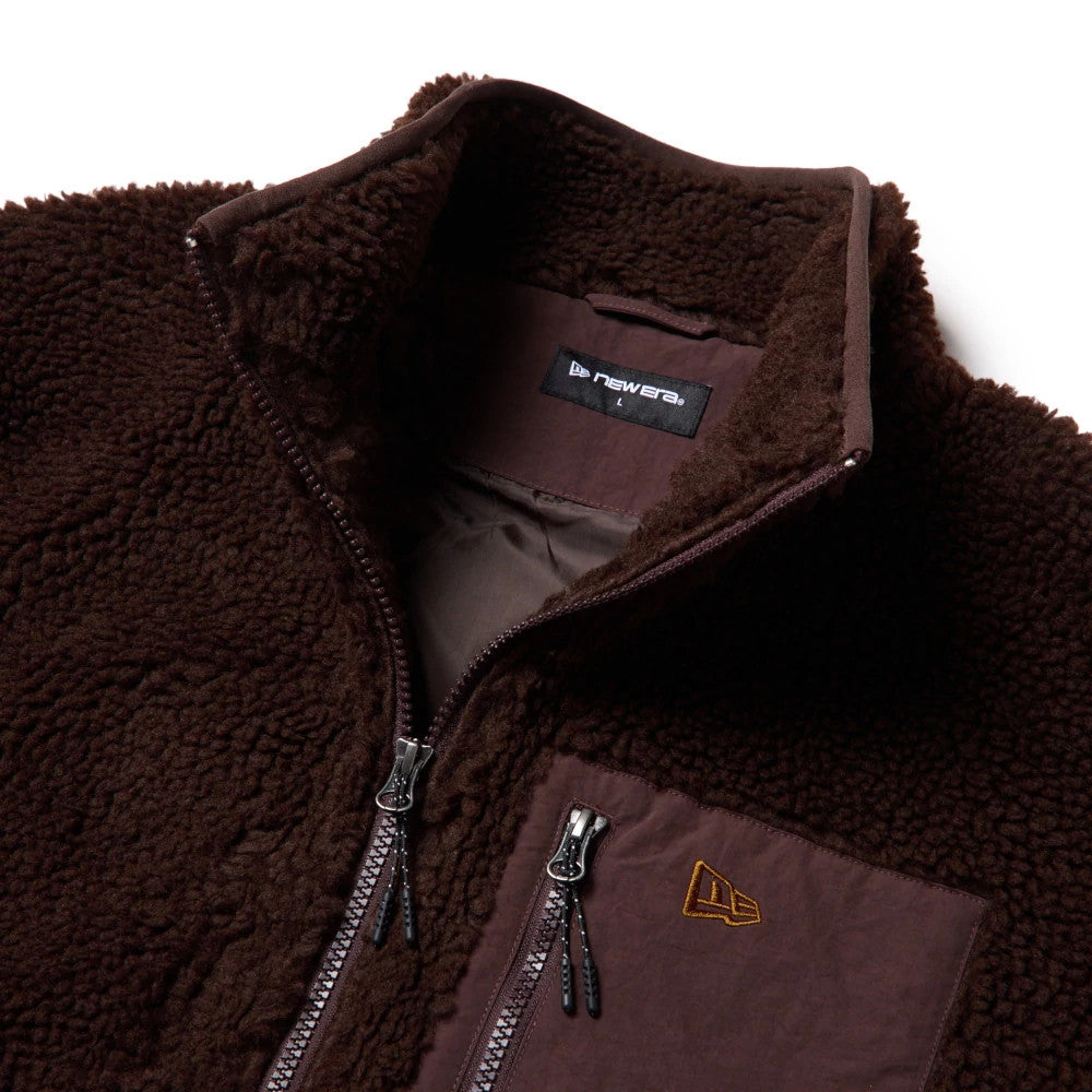 New Era Blouson Dark Brown Jacket, front view showing the rich brown fleece material with a zip closure, angled pocket on the chest, and a raised New Era logo in brown on the pocket.