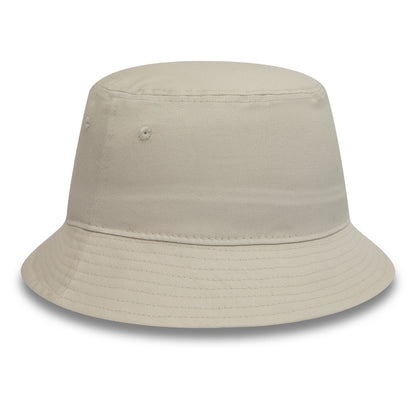 New Era Essential Tapered Stone Bucket Hat, three-quarter view showing unstructured design with sewn eyelets on the sides and a gently sloping brim, crafted in a soft stone-coloured fabric.
