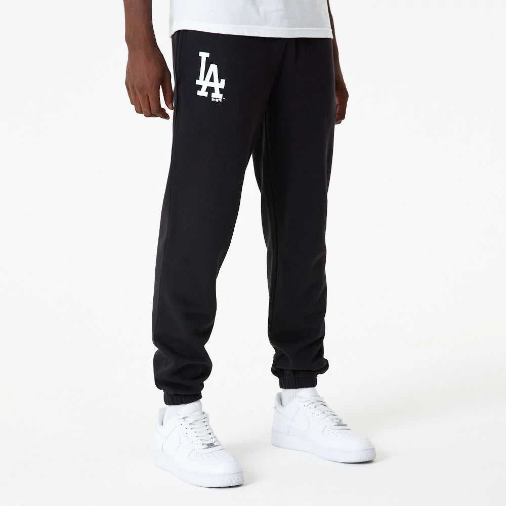 New Era LA Dodgers MLB Essential Black Joggers, front view on a model with an LA logo in white on the upper left leg and black elasticated cuffs, paired with a white T-shirt and white trainers.