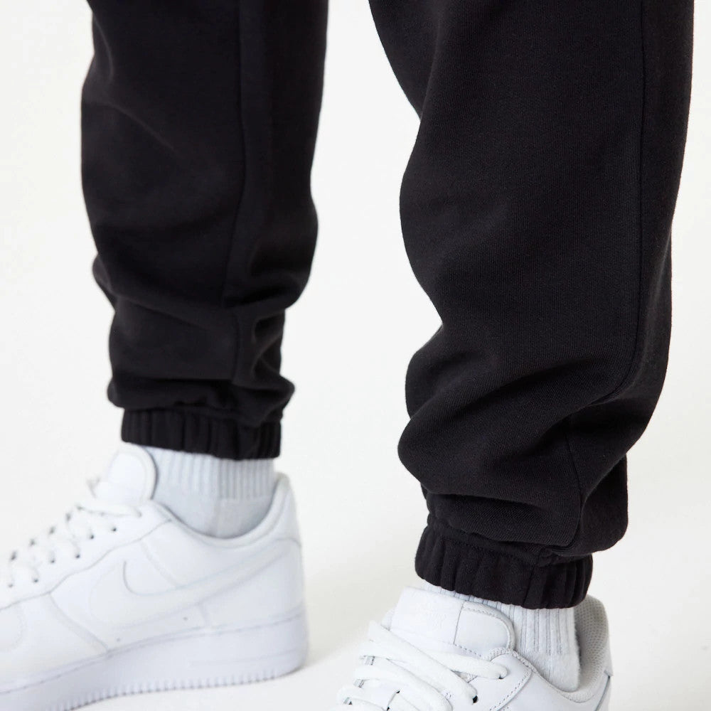 New Era LA Dodgers MLB Essential Black Joggers, close-up on a model showing the elasticated cuffs above white trainers, highlighting the tapered fit and black fabric texture of the joggers.