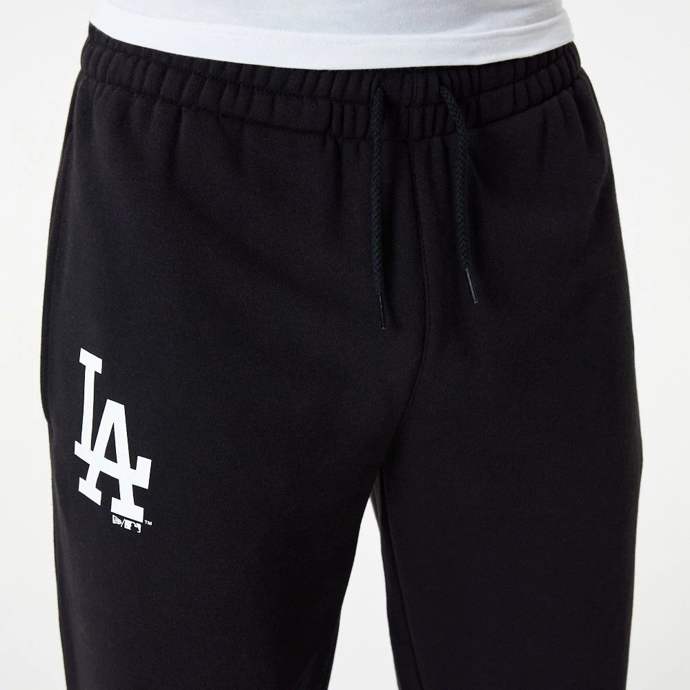 LA Dodgers MLB Essential Black Joggers, front view with the white LA logo screen-printed on the upper left leg, featuring an elasticated waistband with black drawstrings and a slim fit style on a model in a white shirt.