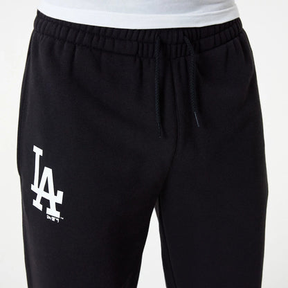 LA Dodgers MLB Essential Black Joggers, front view with the white LA logo screen-printed on the upper left leg, featuring an elasticated waistband with black drawstrings and a slim fit style on a model in a white shirt.