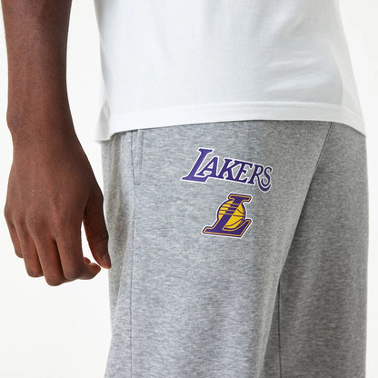 LA Lakers NBA Essential Grey Joggers, side view on a model showing the purple and gold Lakers logo printed on the right thigh, with a close-up of the pocket and a white T-shirt partly visible.