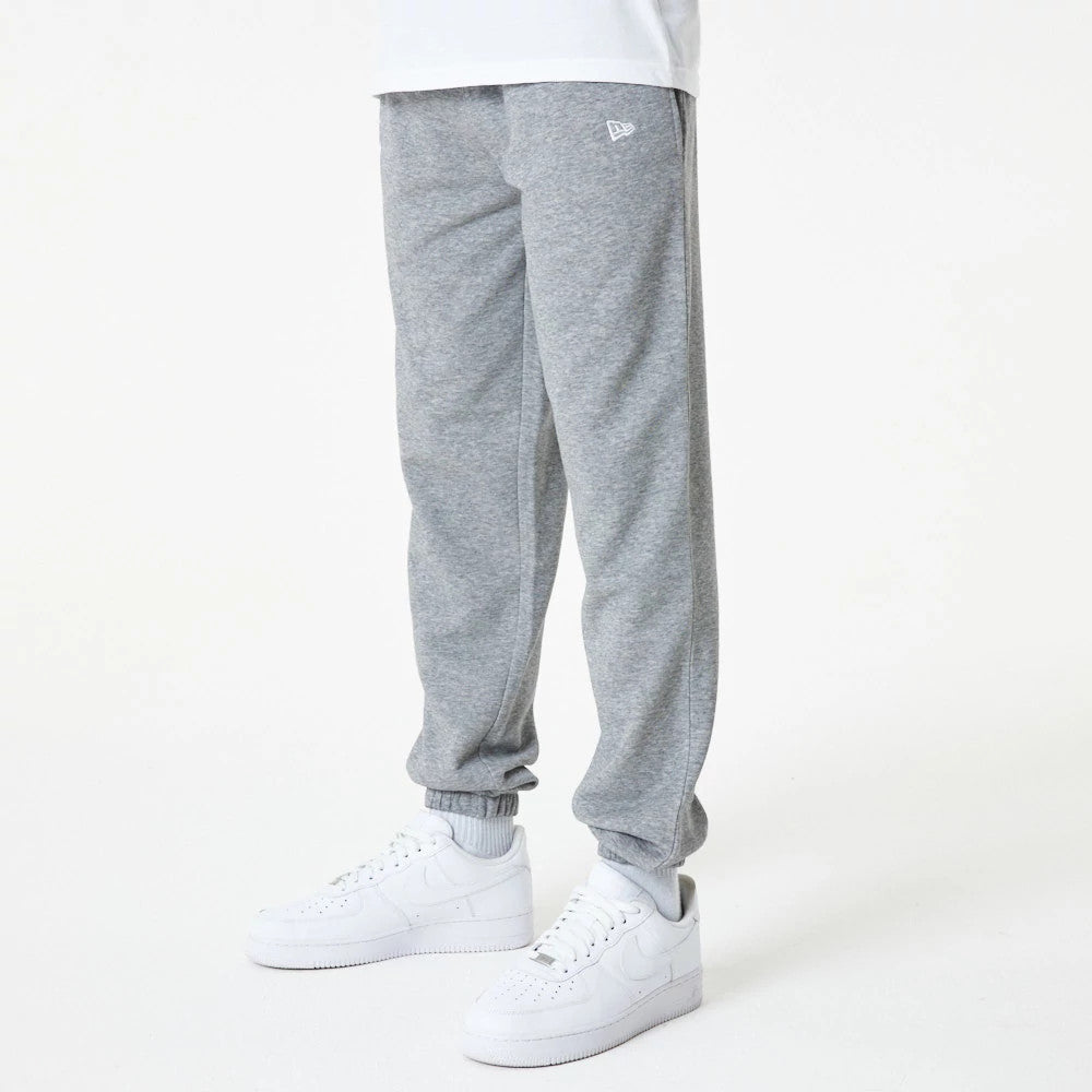 New York Yankees MLB Essential Grey Joggers, front view on a model wearing a white shirt and trainers, featuring a New Era flag logo on the left thigh and ribbed cuffs at the ankles.