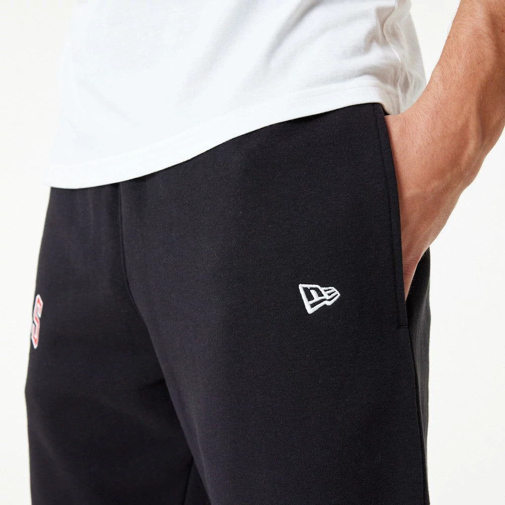 Chicago Bulls NBA Essential Black Joggers, on a model showing the embroidered New Era flag logo in white on the right hip and part of the Bulls logo on the left thigh, styled with a white T-shirt.