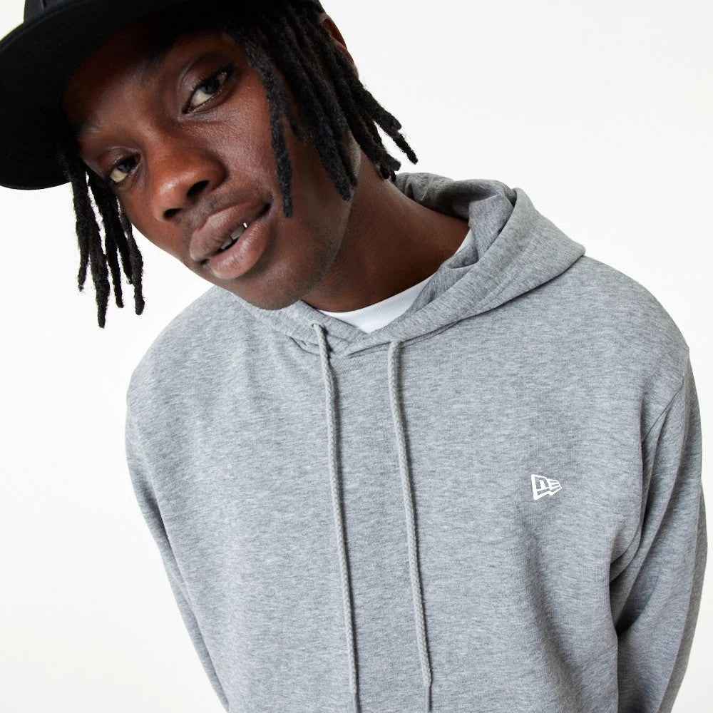New Era Essential Grey Pullover Hoodie, on-model view showing the grey fabric with a white embossed New Era logo on the left chest, a hood with adjustable drawstrings and a relaxed, casual fit.