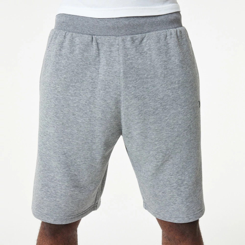 New Era Essential Grey Shorts, front view showing the light grey colour with an elastic waistband, slightly tapered legs, and a subtle debossed New Era logo on the left side near the seam.