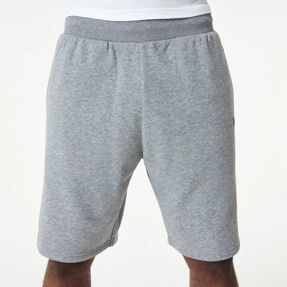 New Era Essential Grey Shorts, front view showing the light grey colour with an elastic waistband, slightly tapered legs, and a subtle debossed New Era logo on the left side near the seam.