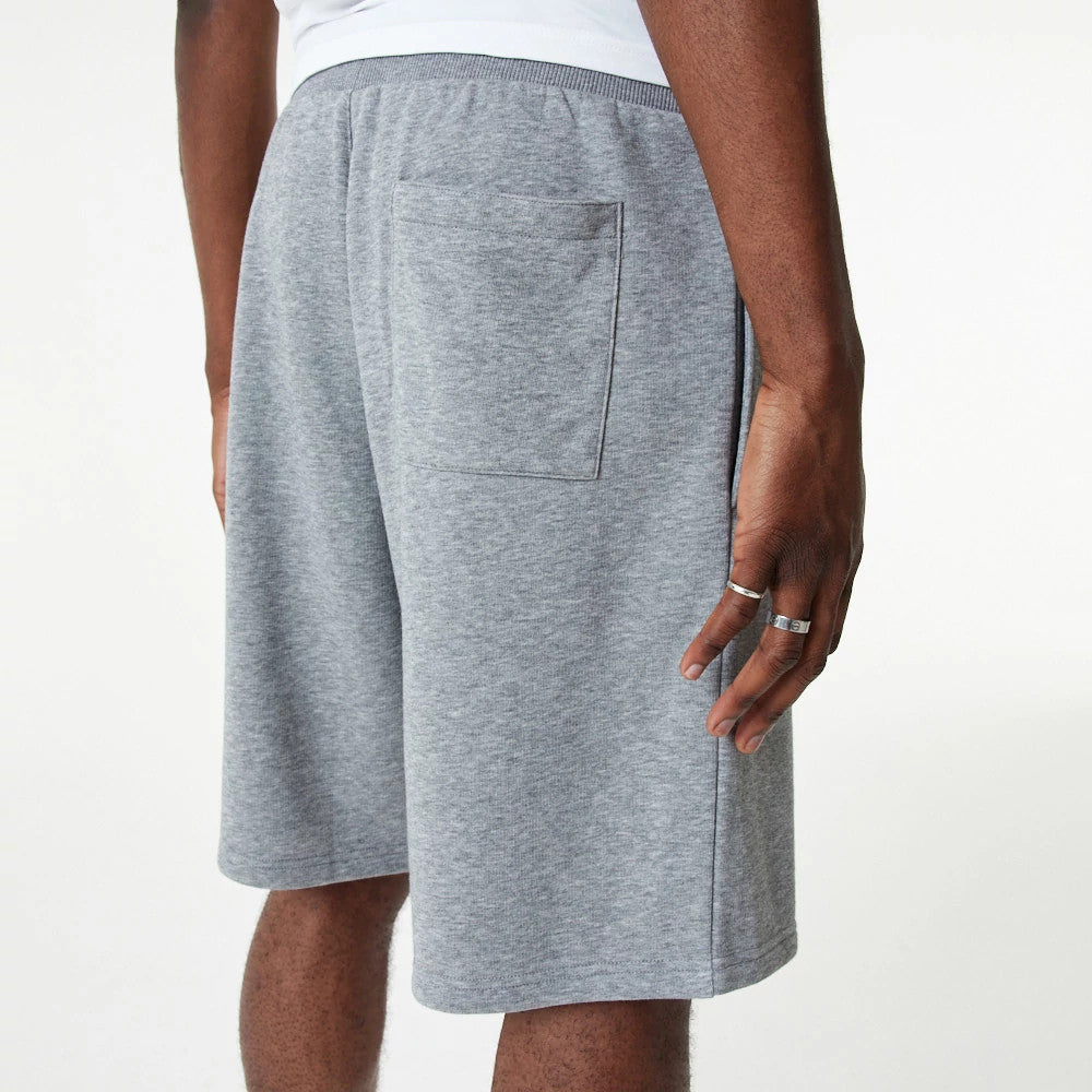 New Era Essential Grey Shorts, rear view showing the light grey fabric with a single patch pocket on the right side, elastic waistband contrasting slightly in a darker grey, worn by a model.