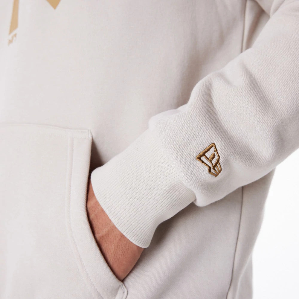 New York Yankees MLB Regular Light Beige Pullover Hoodie, side view showing a hand in the front pocket, a raised New Era logo on the cuff of the sleeve, and the light beige fabric making up the body of the hoodie.