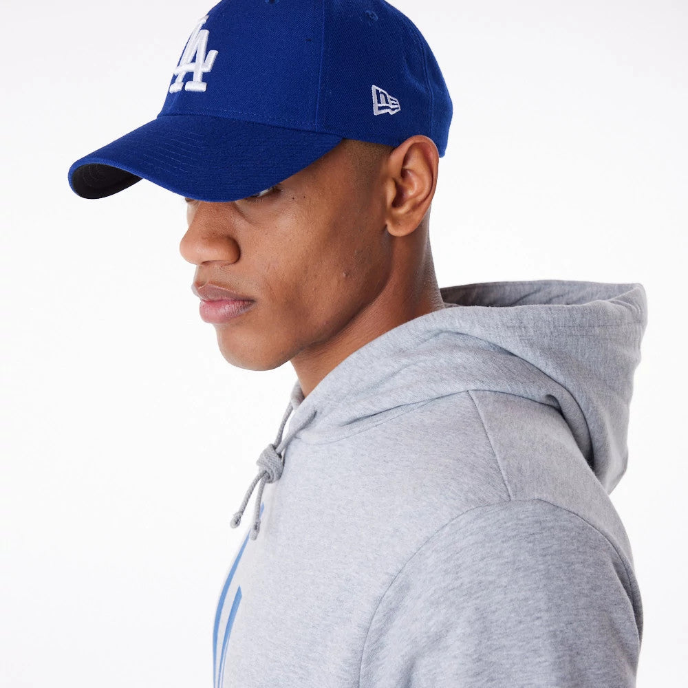 LA Dodgers MLB Regular Grey Pullover Hoodie, on-model side view showing the upper half with the hood down, worn with a blue cap featuring a raised white LA logo on the front and a raised New Era logo on the side.