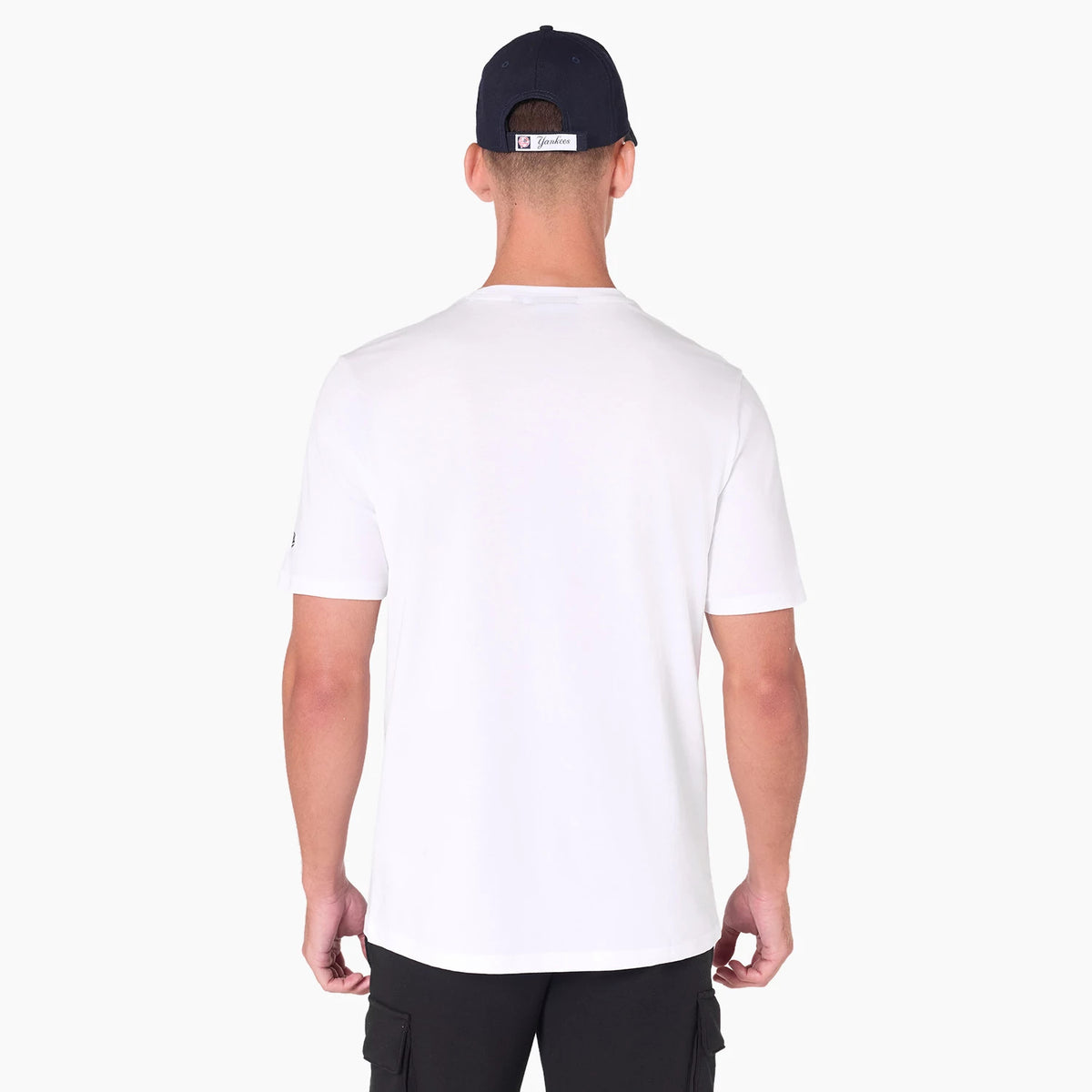 New York Yankees MLB White T-Shirt, rear view showing the plain white back panel, short sleeves with a small New Era logo on the left sleeve, worn by a model also wearing a navy cap.