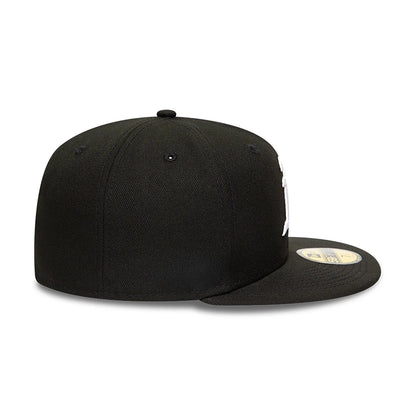Athletics MLB Black and White New Era 59FIFTY Fitted Cap, side view showing the flat black visor with a gold 59FIFTY size sticker and the embroidered logo on the front panel, with a structured black crown and black eyelets.