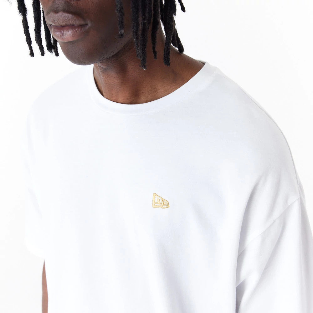 New Era Sticker White Oversized T-Shirt, front view showing a plain white fabric with a small raised gold New Era logo on the left side of the chest, round neckline and short sleeves.