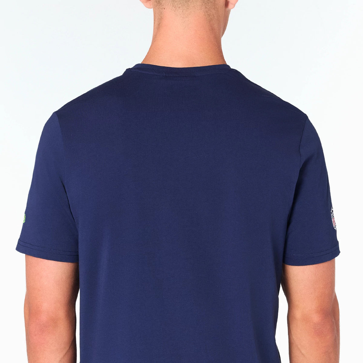 New Era Seattle Seahawks NFL Navy T-Shirt, rear view showing the plain navy back with a round neckline, short sleeves, and a raised Seattle Seahawks logo on the left sleeve near the cuff.