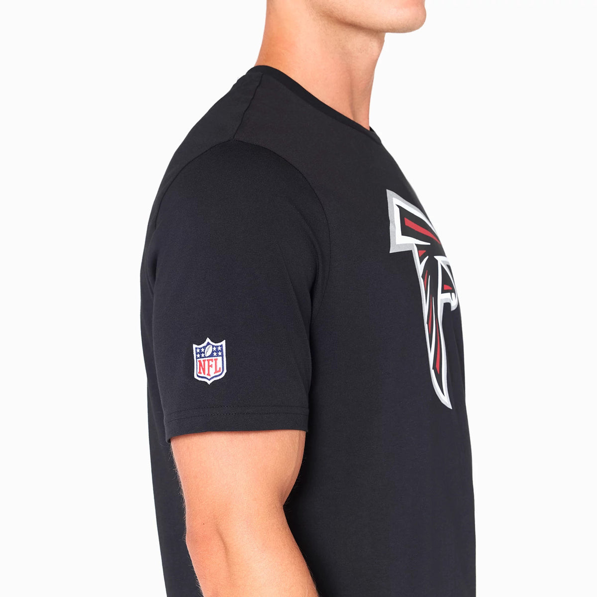 New Era Atlanta Falcons NFL Black T-Shirt, side view showing a large Falcons logo printed on the chest, the black fabric extending to the short sleeves, and a small embroidered NFL shield logo on the upper left sleeve.