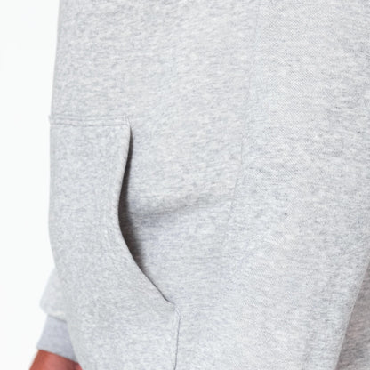 New Era Washington Wizards NBA Grey Pullover Hoodie, side view showing a plain light grey body with a kangaroo pocket opening on the left side waist and ribbed cuff peeking from the rolled sleeve.