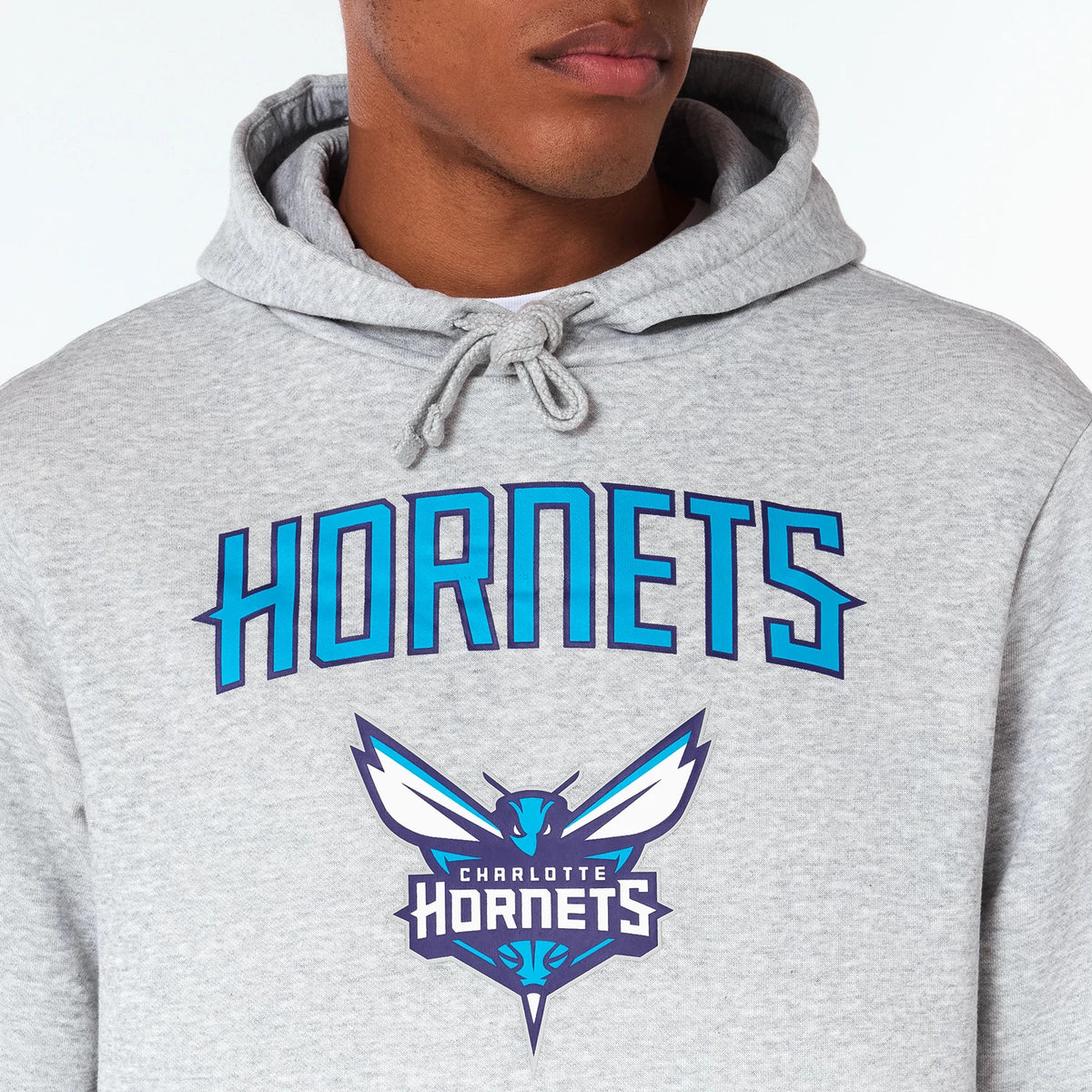 New Era Charlotte Hornets NBA Grey Pullover Hoodie, front view showing the grey fabric with a drawstring hood, large Hornets text in blue across the chest, and a blue and white Charlotte Hornets logo beneath it.
