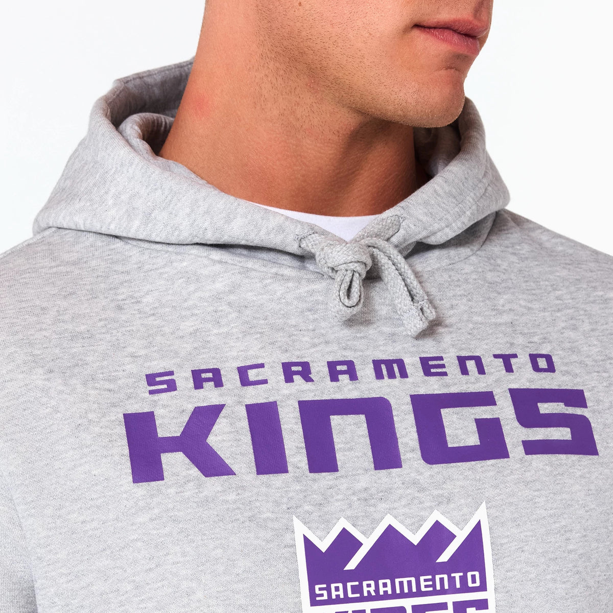 New Era Sacramento Kings NBA Grey Pullover Hoodie, front view showing the grey fabric with a large purple SACRAMENTO KINGS text across the chest, a drawstring hood, and a purple raised logo beneath the text.