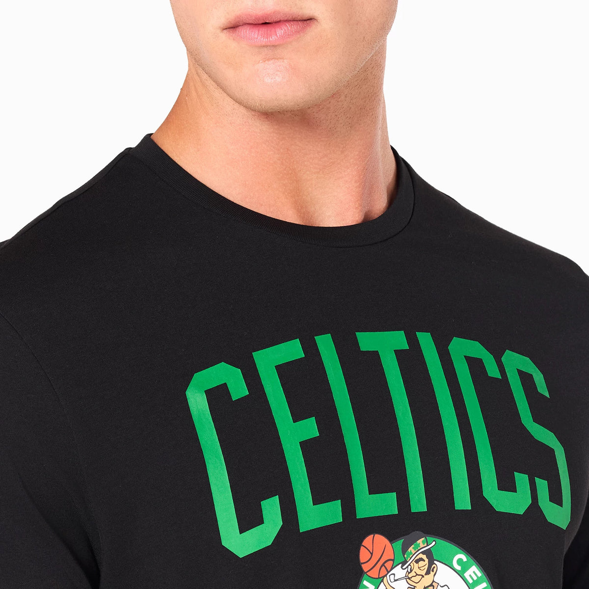 New Era Boston Celtics NBA Black T-Shirt, on-model view showing the chest print with large green CELTICS lettering above the detailed team logo featuring a leprechaun holding a basketball, set on a black background.