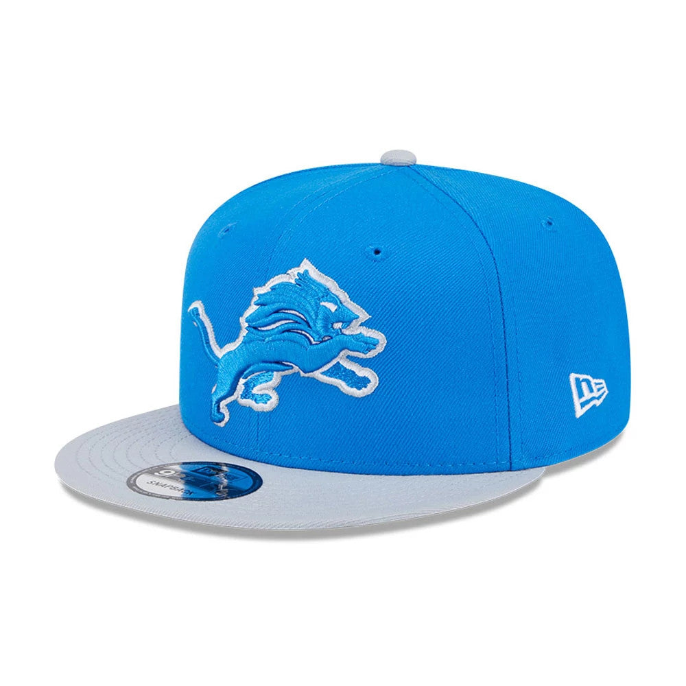 Detroit Lions NFL Evergreen Blue New Era 9FIFTY Snapback Adjustable Cap, front view showing a blue raised embroidered lion logo on the front panel, grey visor with a 9FIFTY size sticker, and New Era flag logo on the left side.