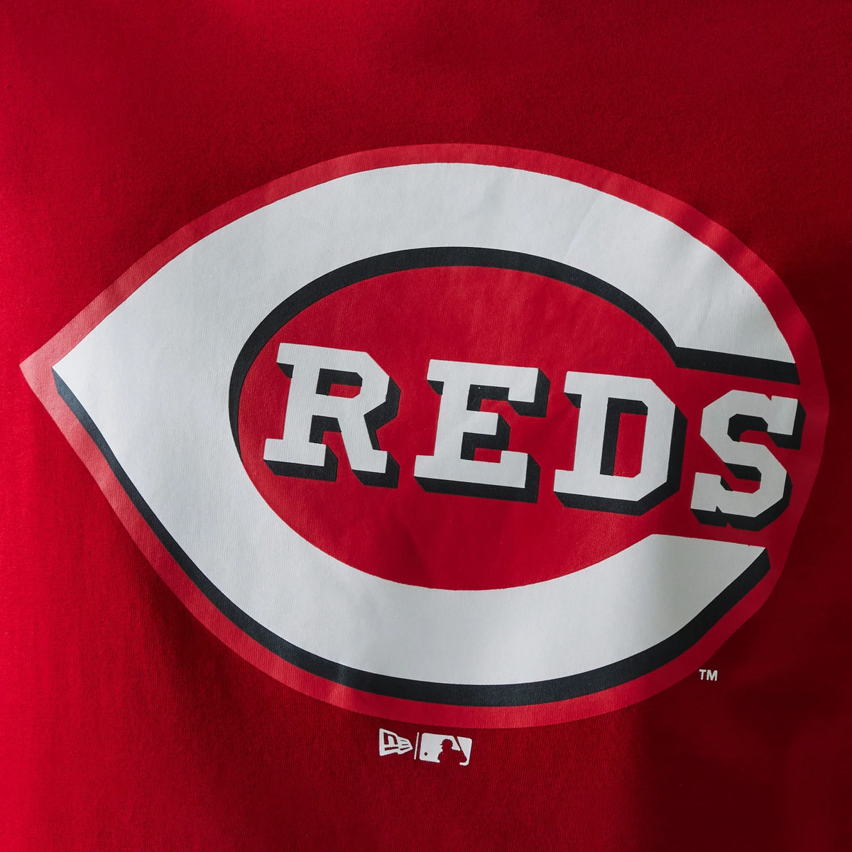 New Era Cincinnati Reds MLB Regular Red T-Shirt, front view showing a large centred white and red 'Reds' logo with black shadowing, the New Era logo and MLB logo printed in white underneath on the red fabric.
