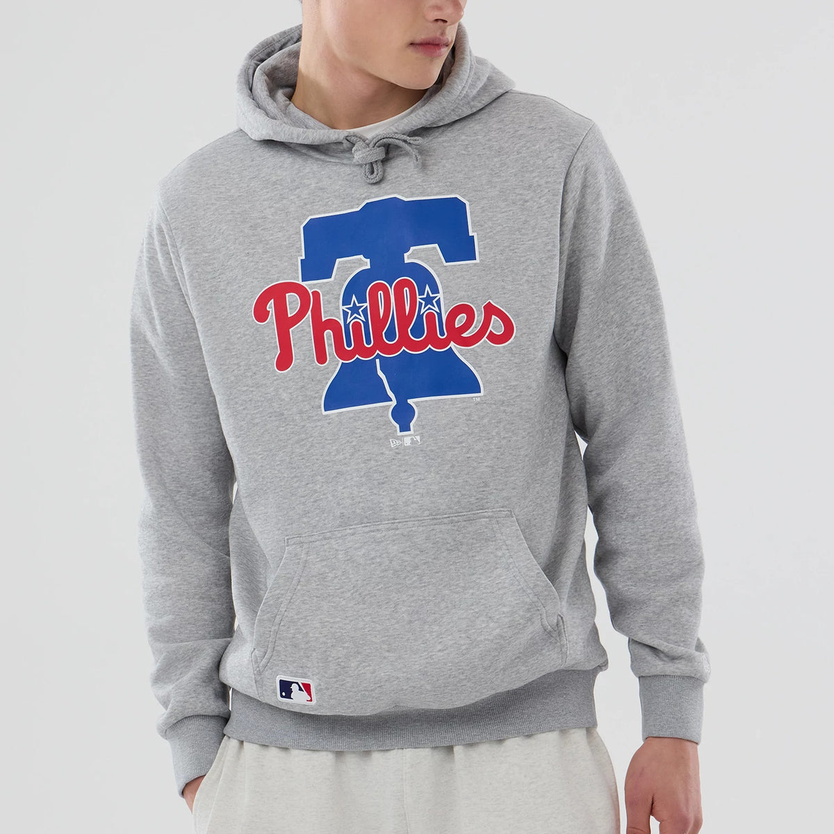 New Era Philadelphia Phillies MLB Grey Pullover Hoodie, front view showing the large blue Liberty Bell graphic with a red Phillies script across the chest, adjustable drawstring hood and ribbed cuffs above a kangaroo pocket.