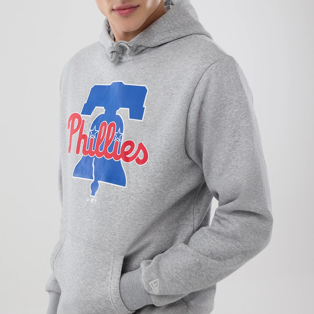 New Era Philadelphia Phillies MLB Grey Pullover Hoodie, front view with large blue Liberty Bell and red Phillies text on chest, drawstring hood, and raised New Era logo on left wrist near the cuff.