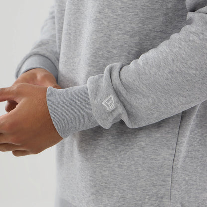 New Era MLB Generic Logo Grey Crew Neck Sweater, close-up showing the ribbed cuff with a white New Era flag logo on the left sleeve, highlighting the soft grey fabric texture and relaxed fit on a model's arm.