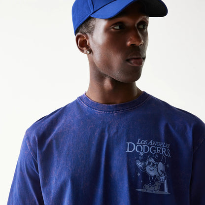 New Era LA Dodgers MLB Character Dark Blue T-Shirt, on-model view showing the front design with a cartoon character and Los Angeles Dodgers text on the chest, worn by a person also wearing a blue cap.