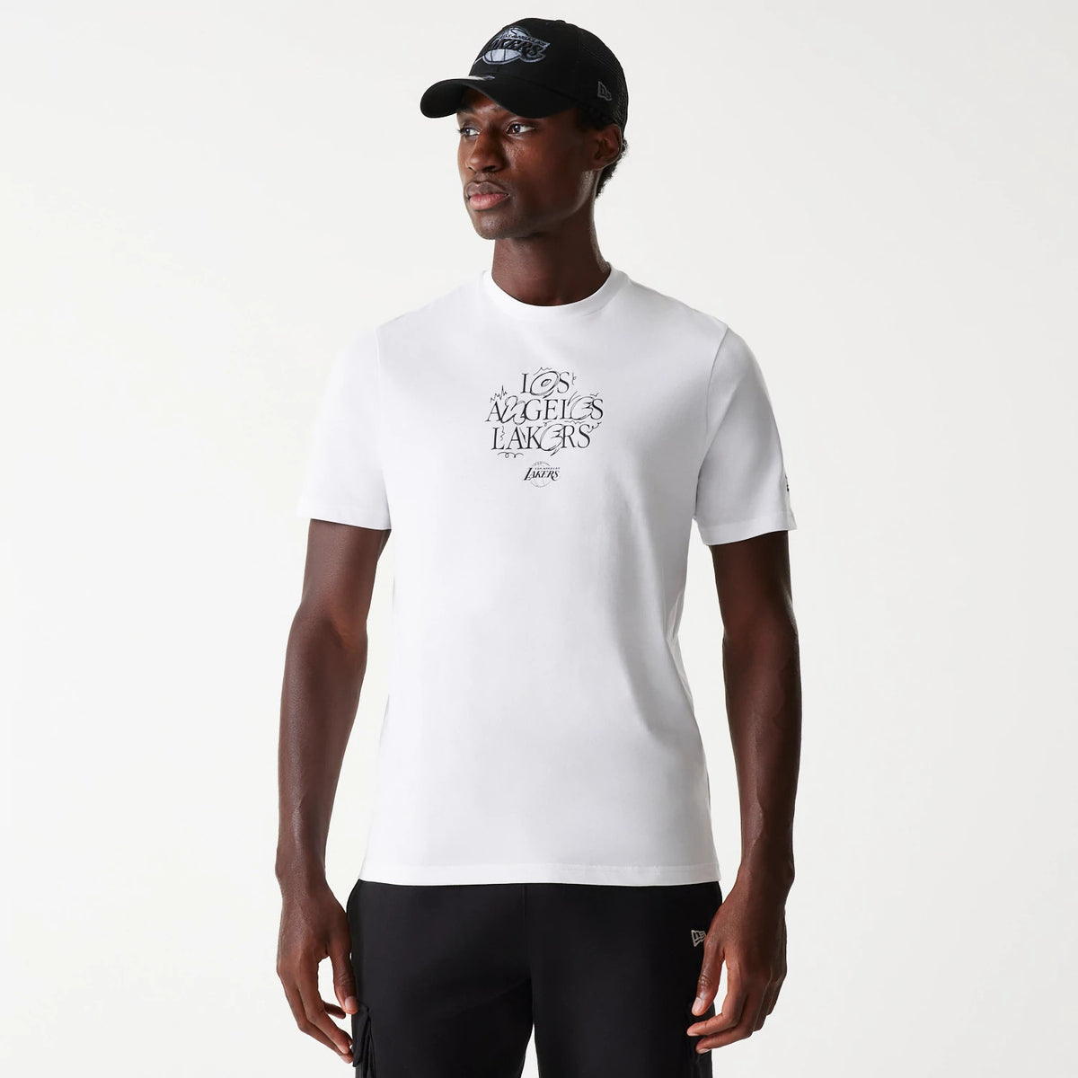 New Era LA Lakers NBA Court Graphic White T-Shirt, on-model view showing the shirt with a bold LA Lakers logo in black on the chest, short sleeves, and a small New Era logo embossed on the left sleeve.