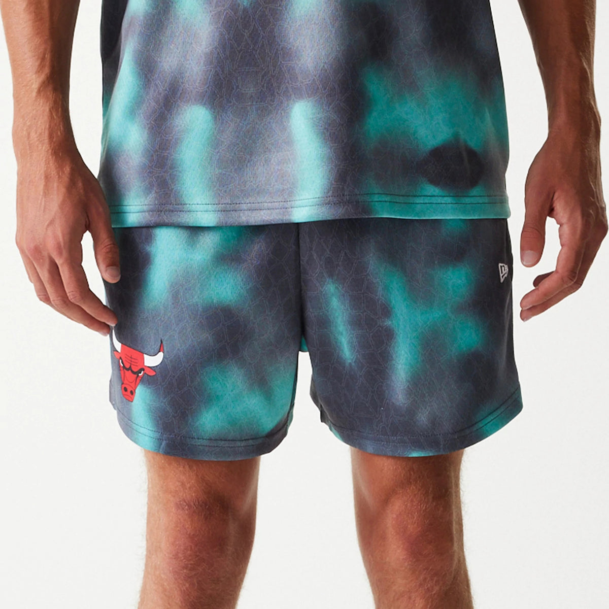 New Era Chicago Bulls NBA All Over Print Green Shorts, front view showing multi-toned green and black pattern with a red Chicago Bulls logo on the left leg and a raised New Era logo near the right hem.