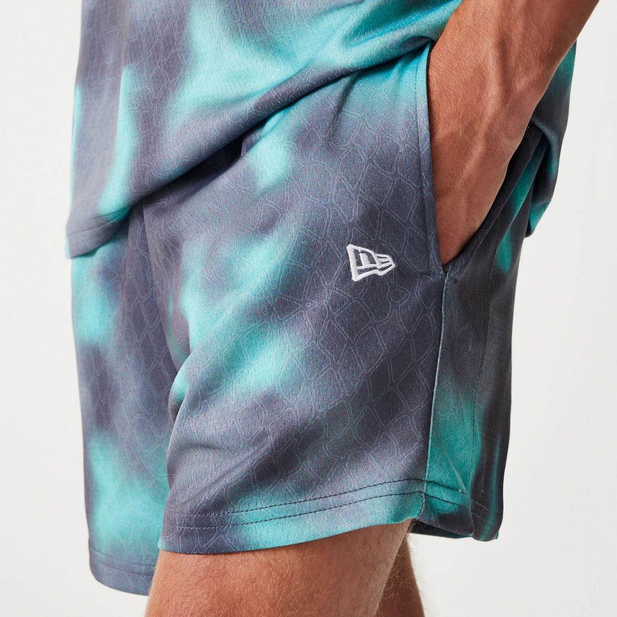 New Era Chicago Bulls NBA All Over Print Green Shorts, side view showing the blend of green and purple shades, a raised white New Era logo near the front pocket, and detailed patterning throughout the fabric.