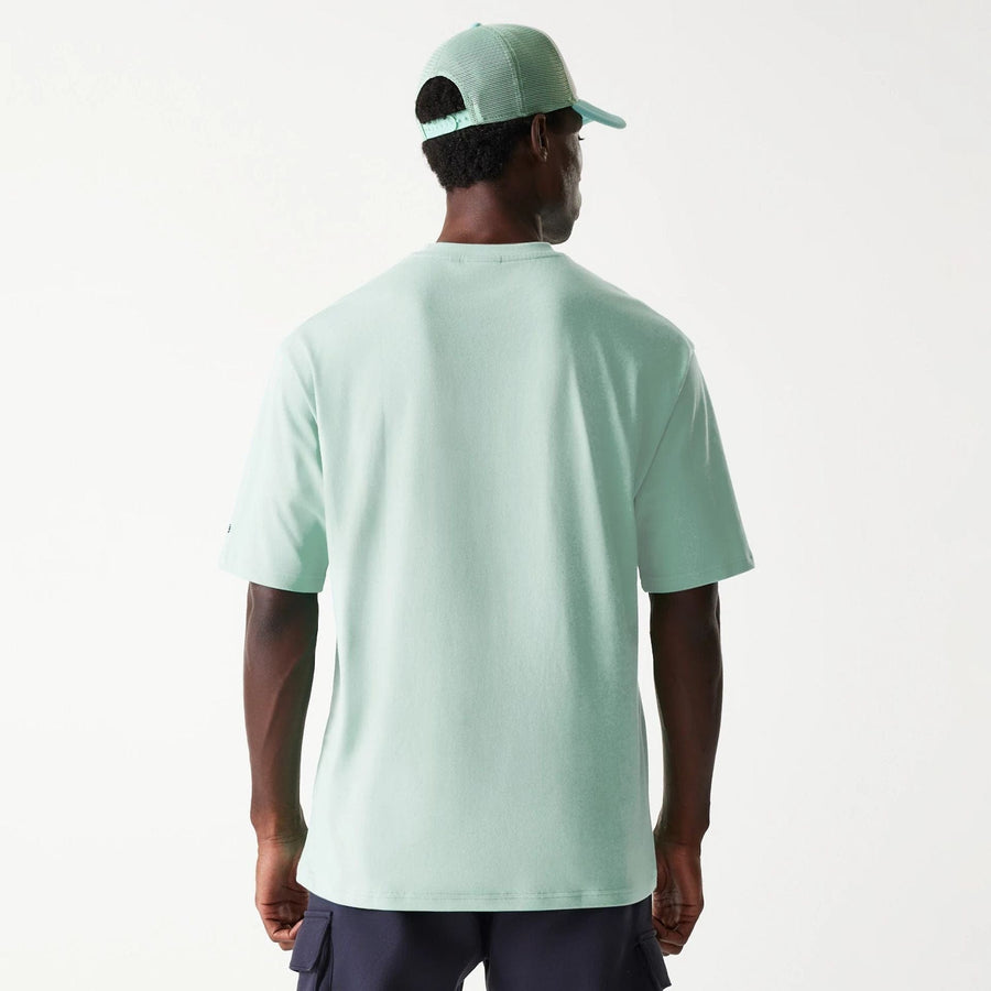 The Male model is wearing New Era Outdoor Graphic Pastel Green Oversized T-Shirt 2